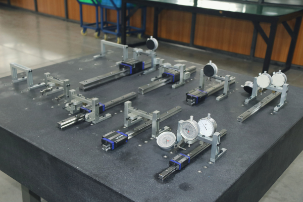 Ein Techniker justiert die Gleitblöcke der Linearführung für einen reibungslosen Lauf und überprüft die Ausrichtung mit Präzisionswerkzeugen. Schwerpunkt sind die Vorspannungseinstellung, die manuelle mechanische Kalibrierung und die professionelle Werkstattumgebung.